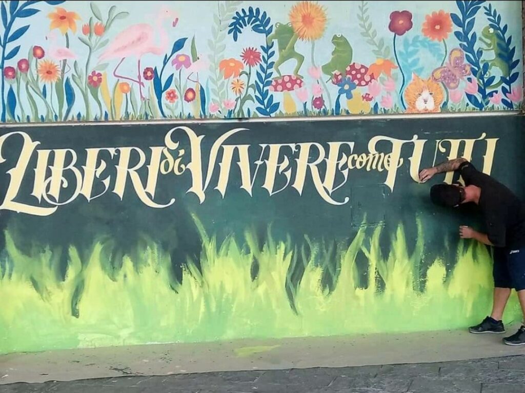 Murales con scritta "Liberi di Vivere come Tutti"